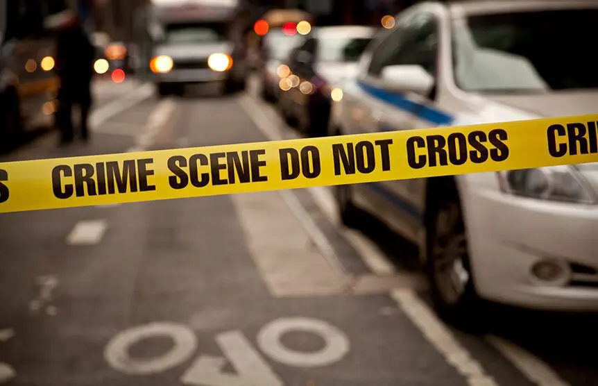 A police tape is shown on the side of a road.