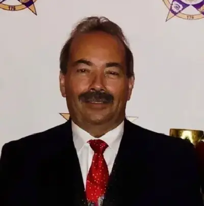 A man in a suit and tie standing next to a wall.