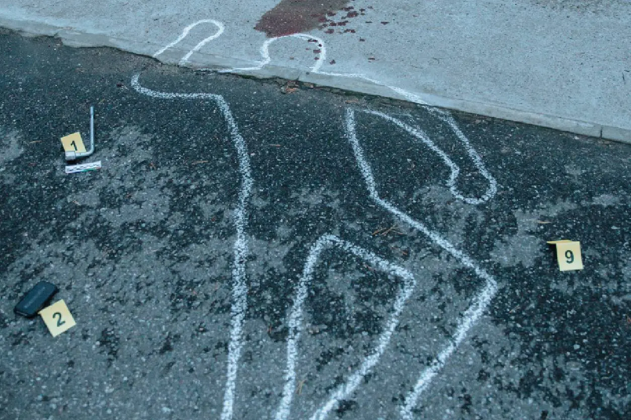 A chalk drawing of a person with blood on the ground.