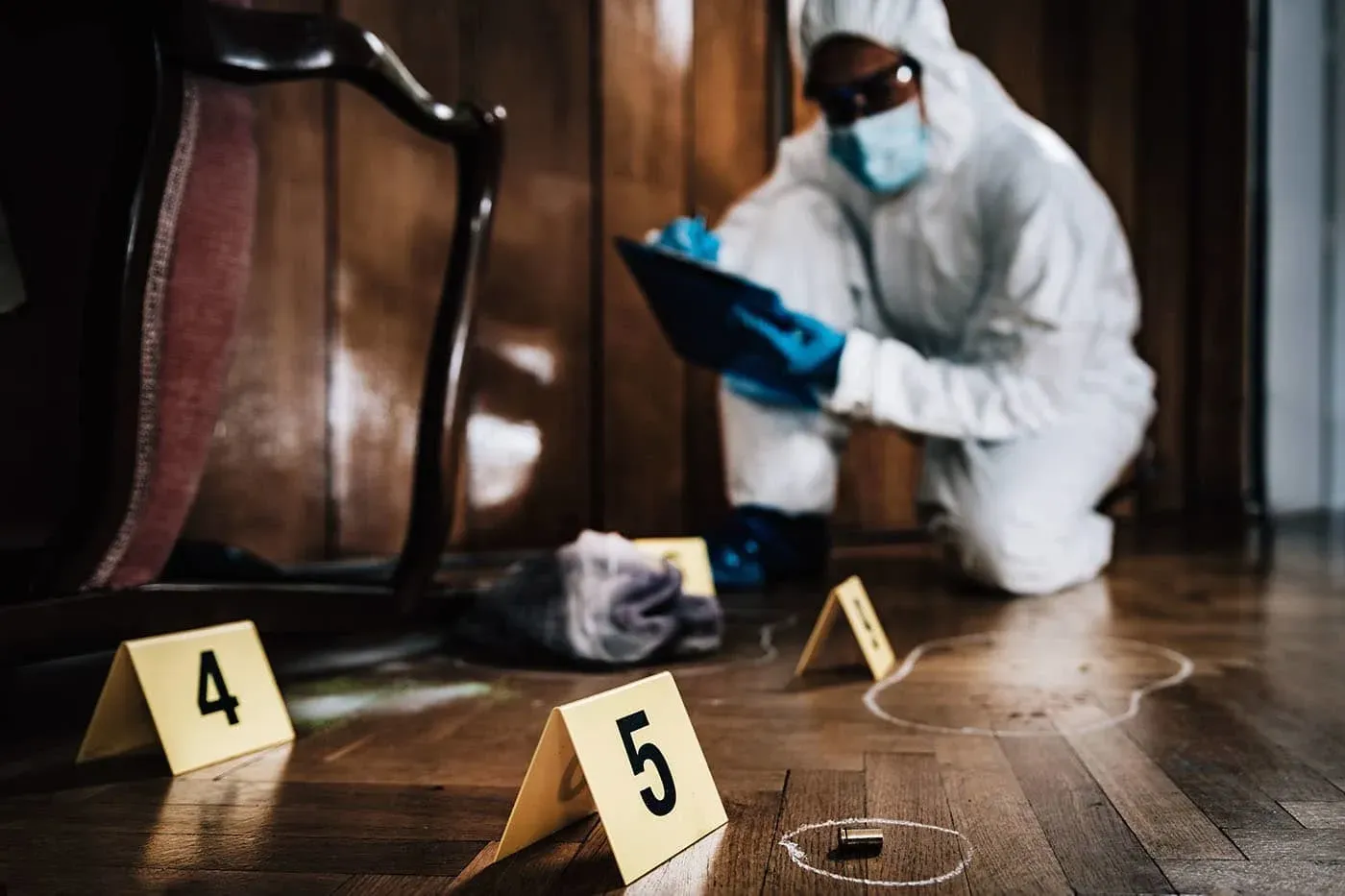 A person in white suit and blue gloves investigating a room.