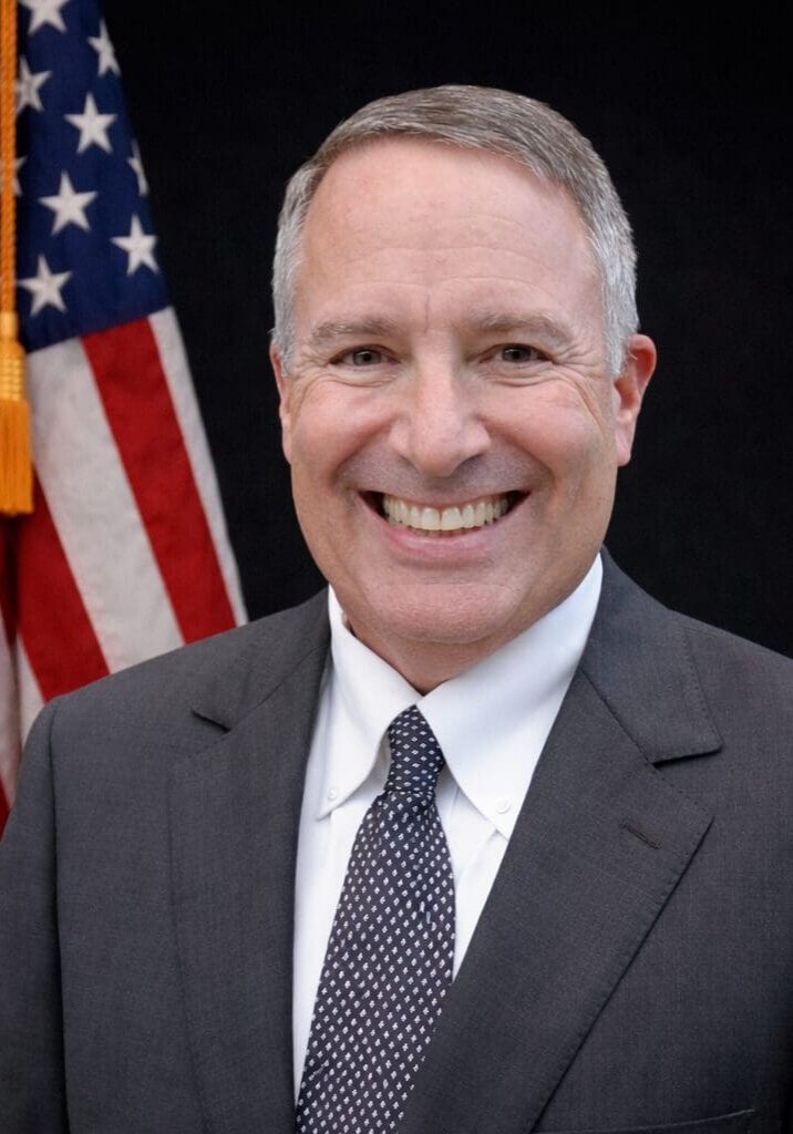 Grinning businessman in suit with flag backdrop