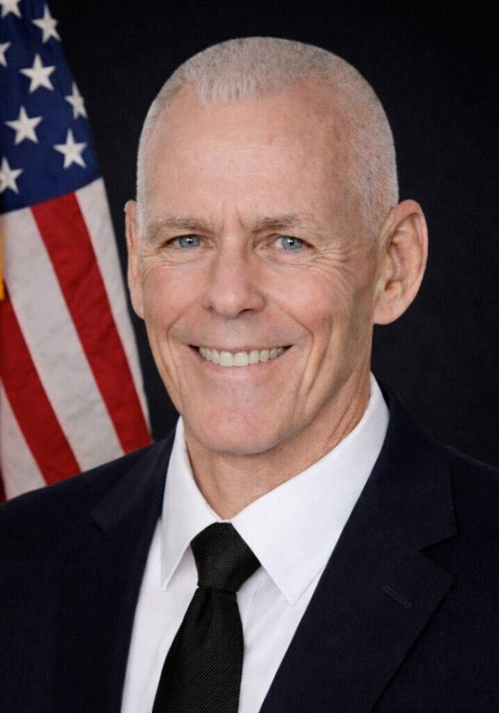 Close-up of man with cropped hair, flag