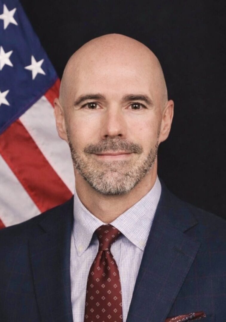 Bald man in suit with American flag