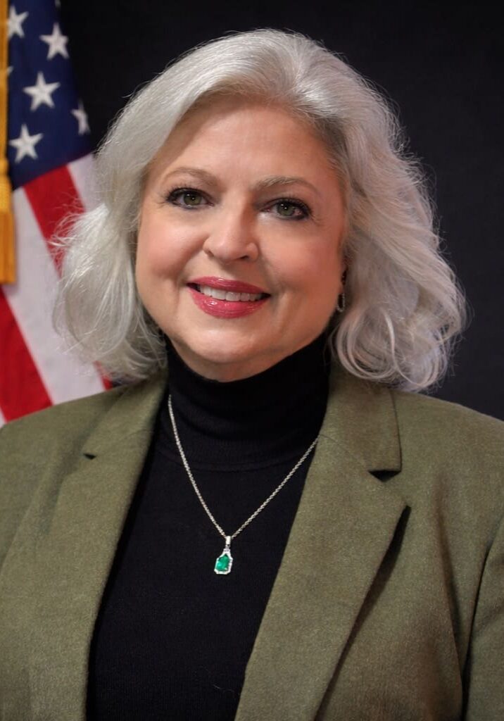 Woman in olive jacket with flag background