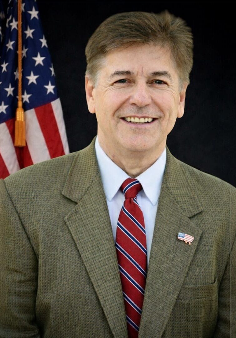 Smiling man in tweed jacket by flag